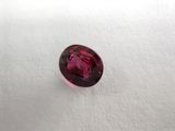 a close up of a red garnet stone on a white surface