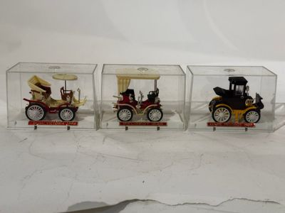 trois petites voitures miniatures dans une boîte transparente posée sur une surface blanche