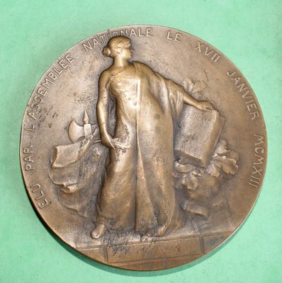 a bronze medal with a woman and a dog on it