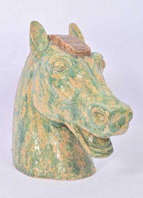 a green and yellow horse head vase on a white background