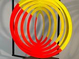 une image représentant une sculpture composée d'un anneau rouge, jaune et bleu