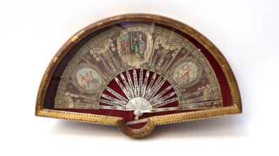 a gold and red fan on a white surface