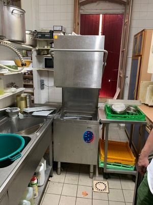 un homme debout dans une cuisine, près d'un évier