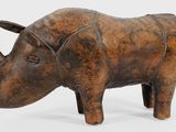 sculpture représentant un rhinocéros debout sur ses pattes arrière, posée sur une surface blanche