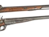 two old guns are sitting side by side on a white surface