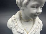 a white busturine of a child with a necklace on it