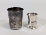 a silver cup next to a silver cup on a white surface