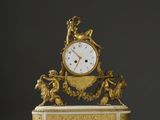 une horloge en or posée sur un socle blanc
