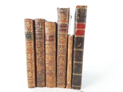 several old books are stacked on top of each other on a white surface