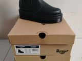black leather boots are stacked on top of boxes on a white floor