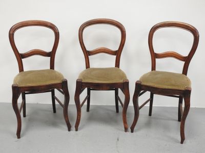 trois chaises en bois aux assises rembourrées vertes, adossées à un mur blanc