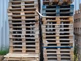 de nombreuses palettes en bois empilées les unes sur les autres devant un bâtiment