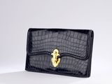a black crocodile skin wallet with a gold lock on the front