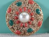 pair of red, green, and gold broochies with a pearl