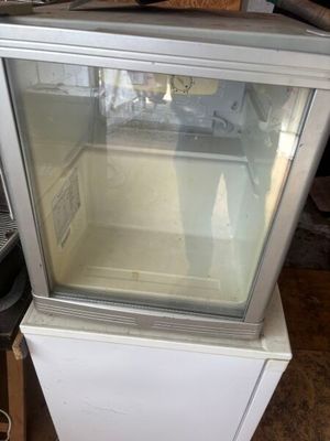 un petit réfrigérateur surmonté d'une porte vitrée