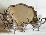 trois théières en argent et un plateau posés sur une table