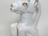 une sculpture en céramique blanche représentant un chien assis par terre