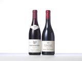 two bottles of red wine sit on a white surface