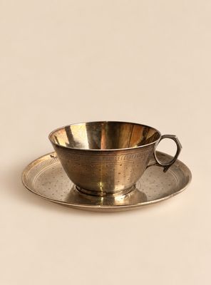 une tasse et une soucoupe en argent posées sur une soucoupe