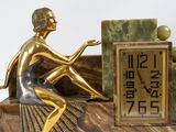 a statue of a woman sitting on a table next to a clock