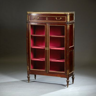 une bibliothèque ancienne en acajou, ornée de montures en laiton et recouverte de velours rouge