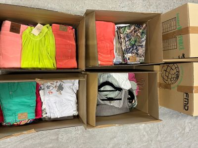 Plusieurs cartons de vêtements sont empilés les uns sur les autres