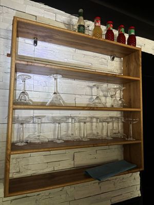 une étagère en bois sur laquelle sont posés des verres à vin et des bouteilles