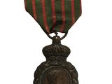 une vieille médaille ornée d'un ruban rouge et vert sur fond blanc