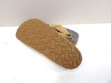 pair of tan slippers on a white surface with a can of soda in the background