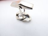 a close up of a pair of silver cufflinks on a white surface