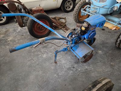 un tracteur bleu équipé d'une charrue, dans un garage