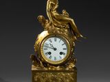 une horloge en or surmontée d'une dame assise