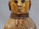 a brown vase with a face and a hat on it