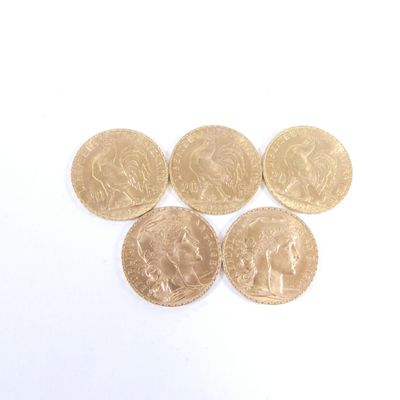 quatre pièces d'or superposées sur une surface blanche