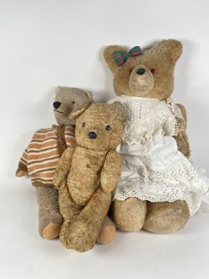 three teddy bears sitting next to each other on a white surface