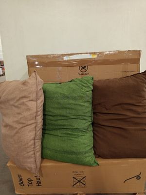 three pillows on a cardboard box in the middle of a room