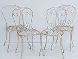 pair of white wrought garden chairs with arms and legs