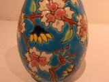 a blue egg with flowers on it sitting on a table