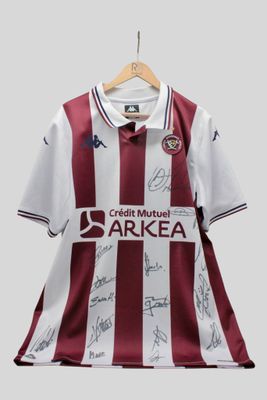 un gros plan sur un maillot de foot sur lequel figurent les signatures des joueurs