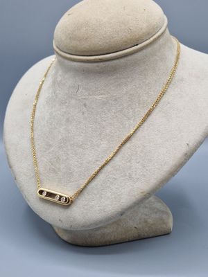 a gold plated necklace with a bar on a mannequin neck