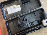 une mallette noire posée par terre, contenant un pistolet