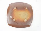 a brown plate with holes in it on a white surface