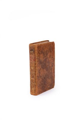 an old book with a brown cover sitting on top of a white surface