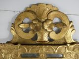 a gold clock on a white wall with a clock on it