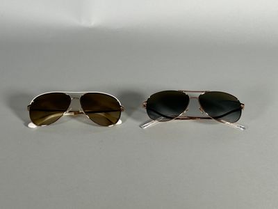 two pairs of sunglasses sitting on top of a white surface