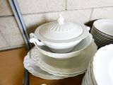 a stack of white plates and bowls on a table