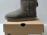 a pair of grey ugg boots sitting on top of a cardboard box