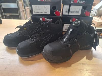 deux paires de bottes de travail noires posées sur une table en bois