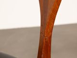the back of a wooden chair with a black leather seat