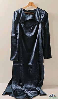 une photo d'une robe noire suspendue à un cintre accroché au mur